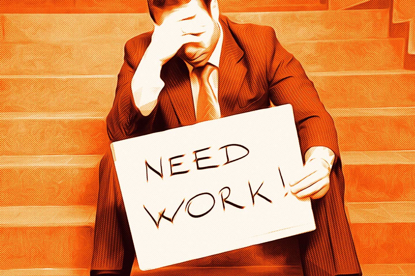 Unemployed man wearing suit and holding sign that says "Need Work!"